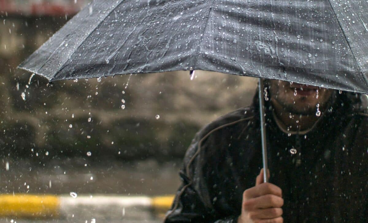 Photo d'un homme tenant un parapluie pour illustrer une météo pluvieuse