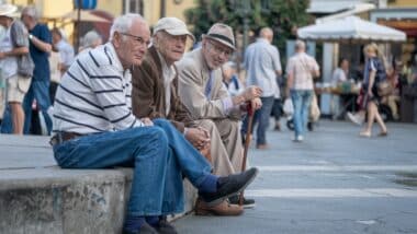 Photo de trois hommes d'un certain âge assis dans une place publique pour évoquer la retraite