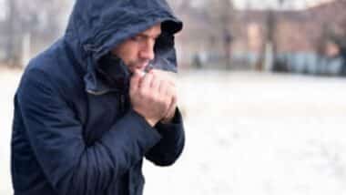 Une homme qui souffle dans ses mains pour illustrer une météo glaciale