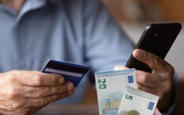 Personne tenant son smartphone et sa carte bancaire