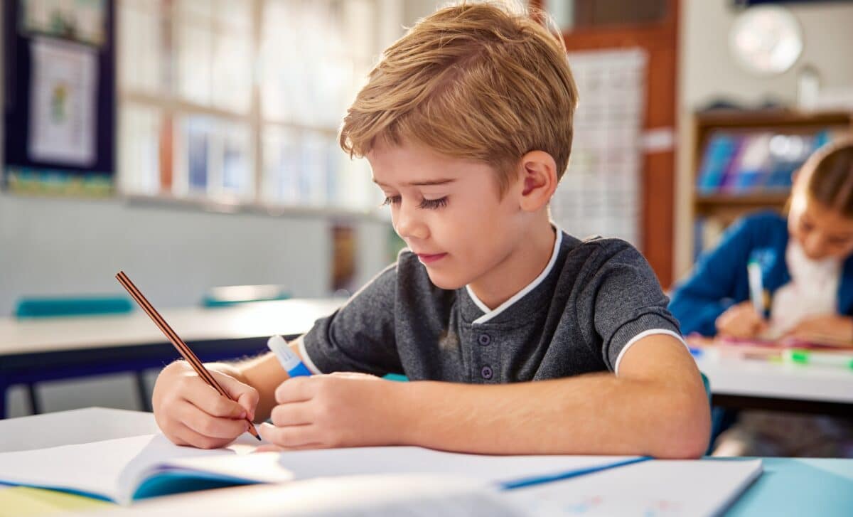 Un enfant écrit dans un cahier à l'école primaire