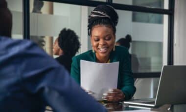 Recruteuse lors d'un salon de l'emploi en train de lire le CV d'un candidat