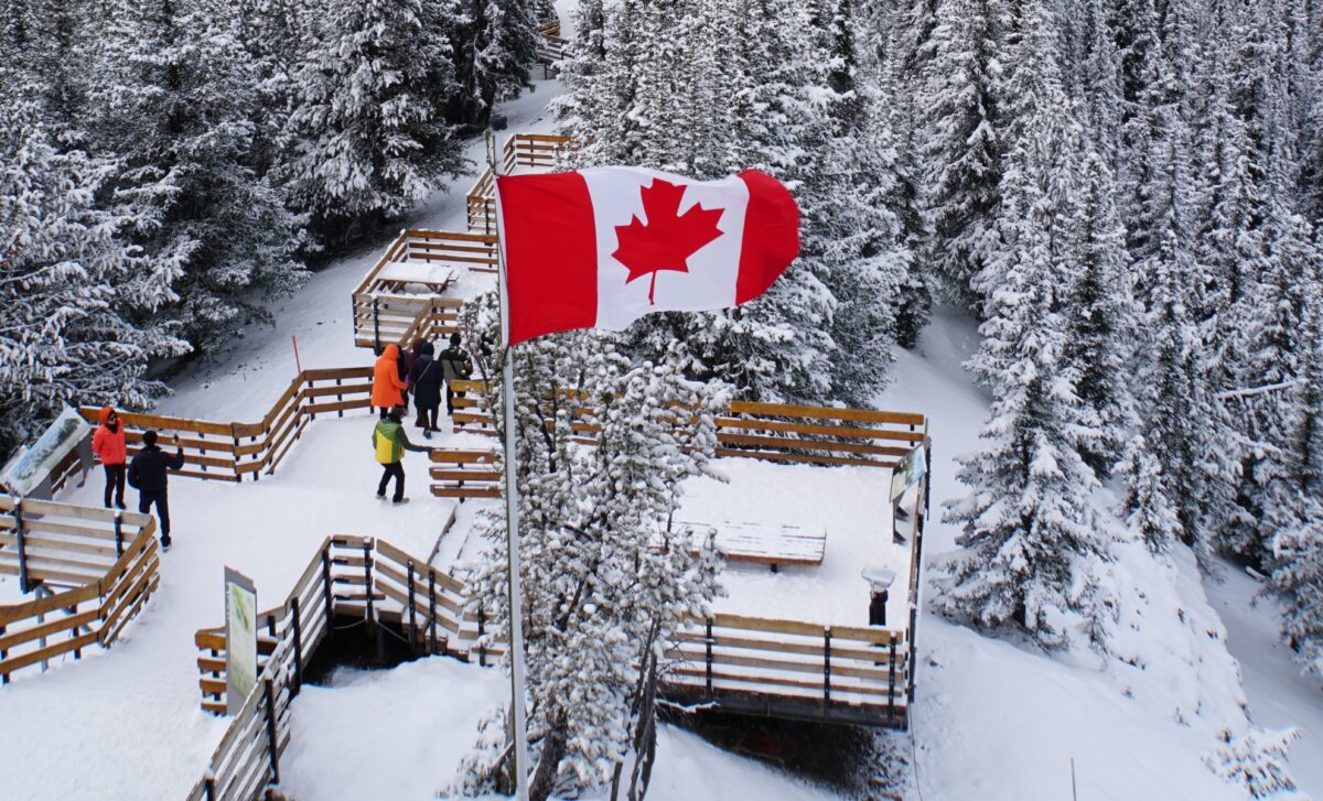 zone recouverte de neige avec le drapeau du canada planté devant