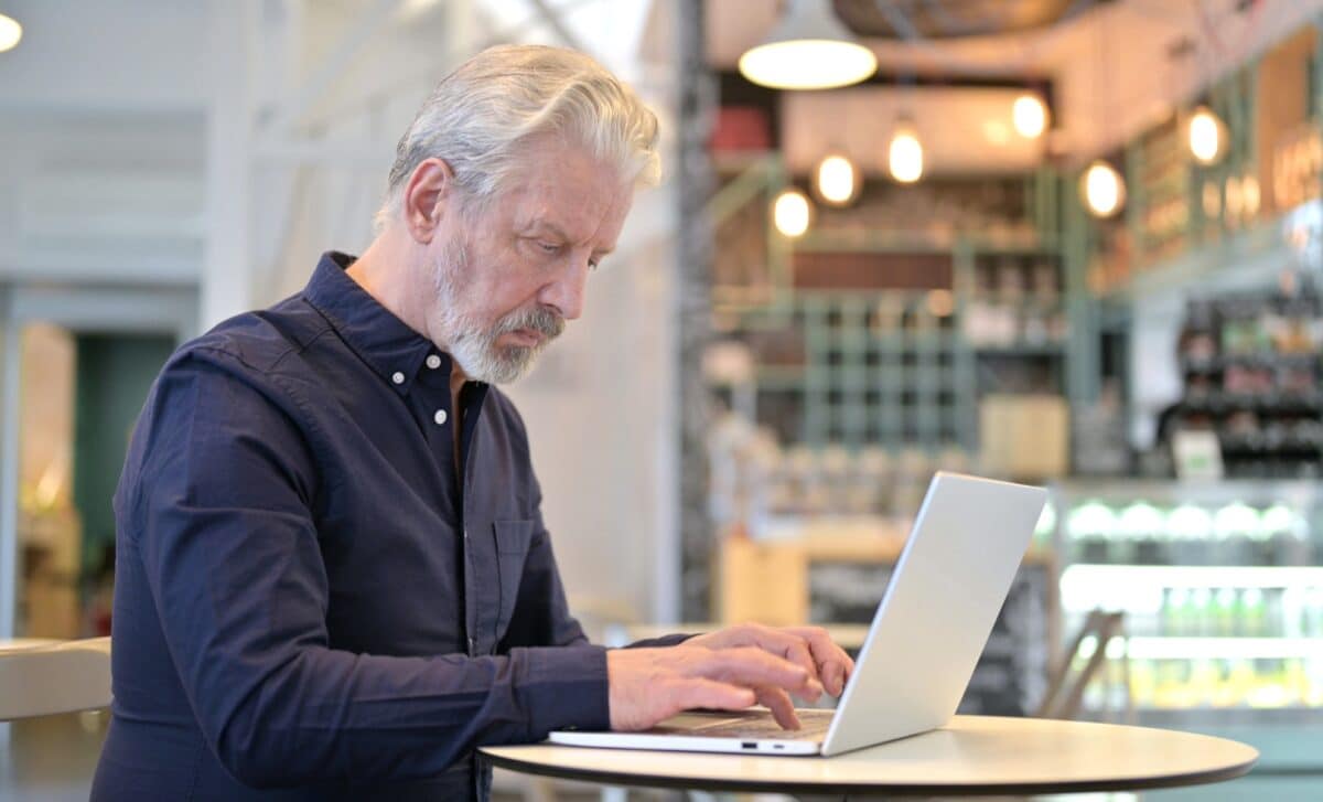 Un senior travaille sur son ordinateur portable dans un café