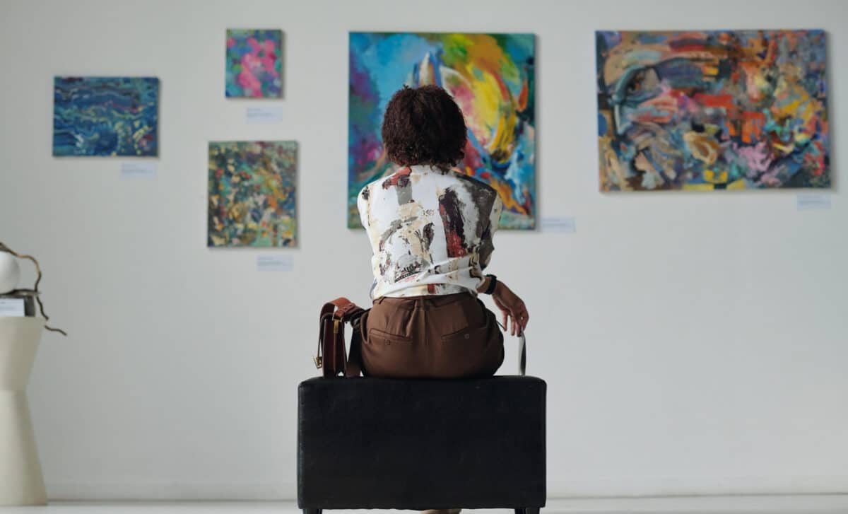 jeune femme assise sur un canapé et regardant des tableaux au mur