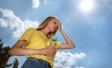 Femme avec une bouteille d'eau souffrant d'un coup de chaleur à l'extérieur