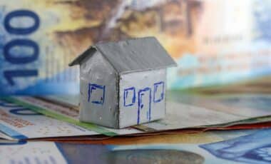 Une maquette en carton d'une maison individuelle est placée devant des billets de banque suisses