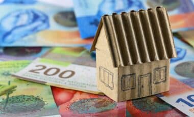 Une maquette en carton d'une maison individuelle est placée devant des billets de banque suisses