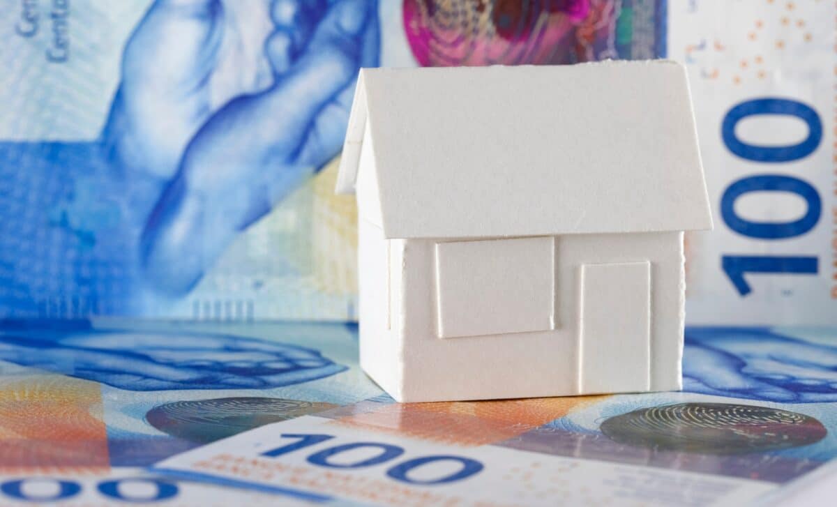 modèle de maison détachée en papier repose sur des billets suisses