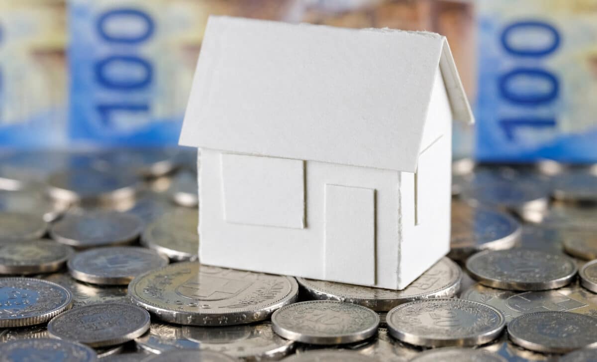 Modèle d'une maison individuelle en papier blanc sur les pièces de monnaie suisses