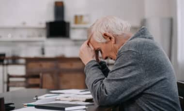 homme âgé assis à une table avec des factures