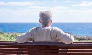 homme âgé détendu assis sur un banc, face à la mer