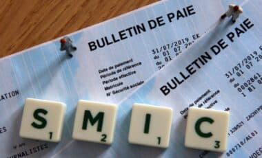 Un scrabble formant le mot Smic sur deux bulletins de paie