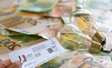 Des billets d'argent posés sur une table et une main tient le chèque énergie