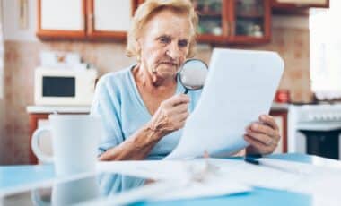 Photo d'une femme senior consultant un document pour illustrer les aides aux personnes sans retraite