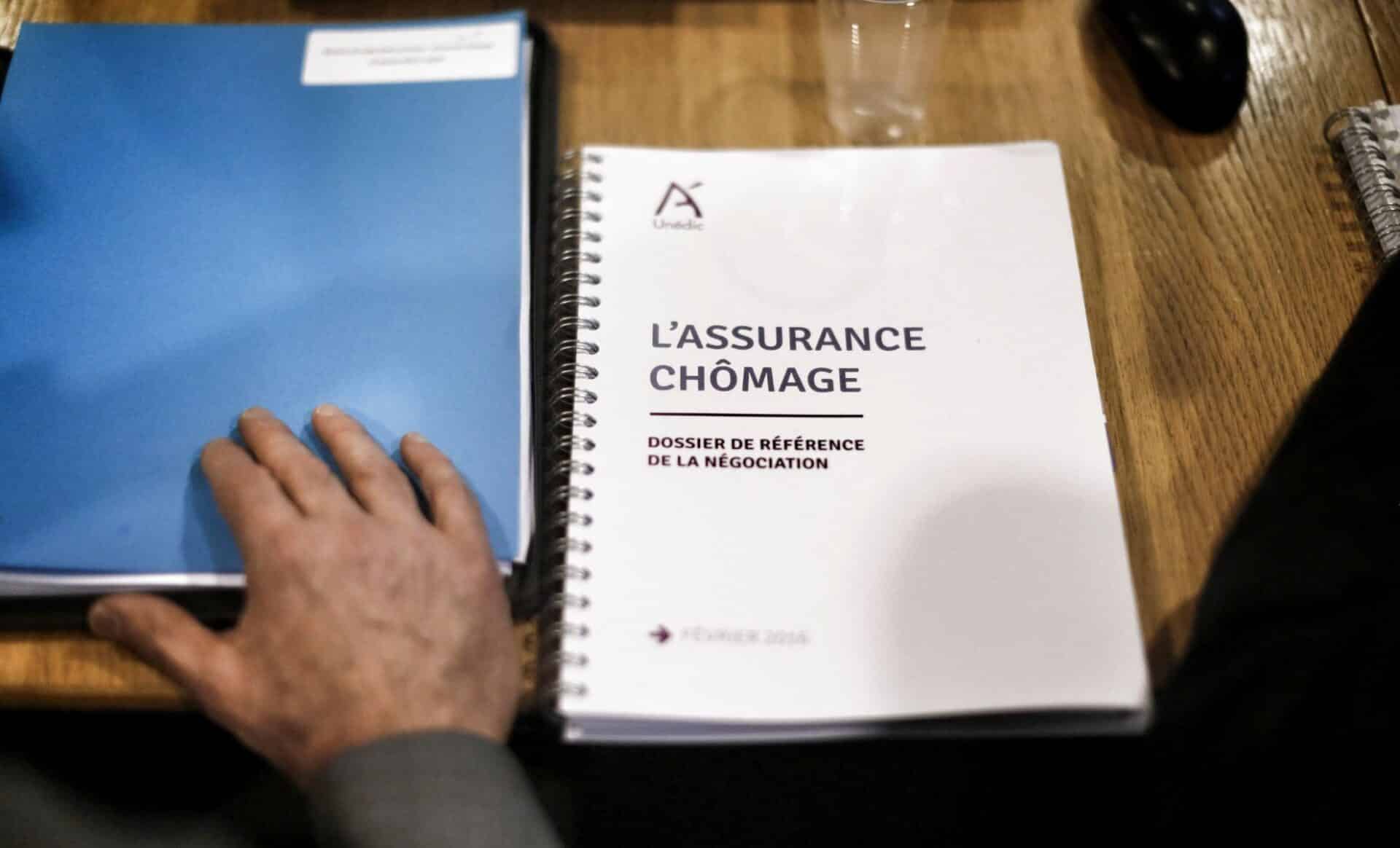 Deux dossiers posees sur une table, dont l'un d'eux porte le titre de l'Assurance chômage