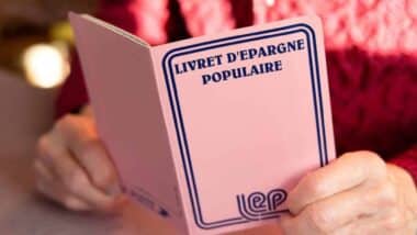 Une personne tenant un livret d'épargne populaire (LEP) de couleur rose