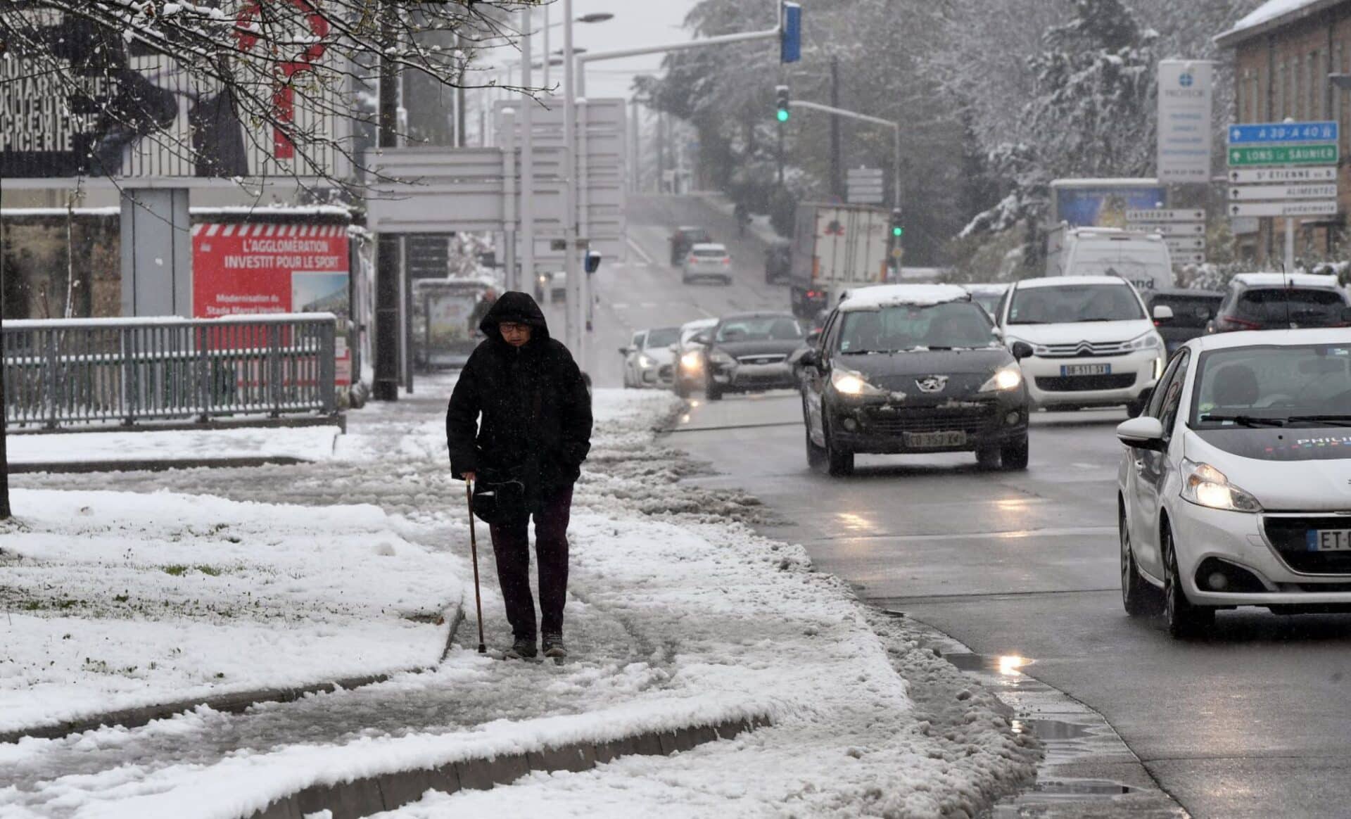 Une personne marchant sur un trottoir couvert de neige symbolisant une météo perturbée