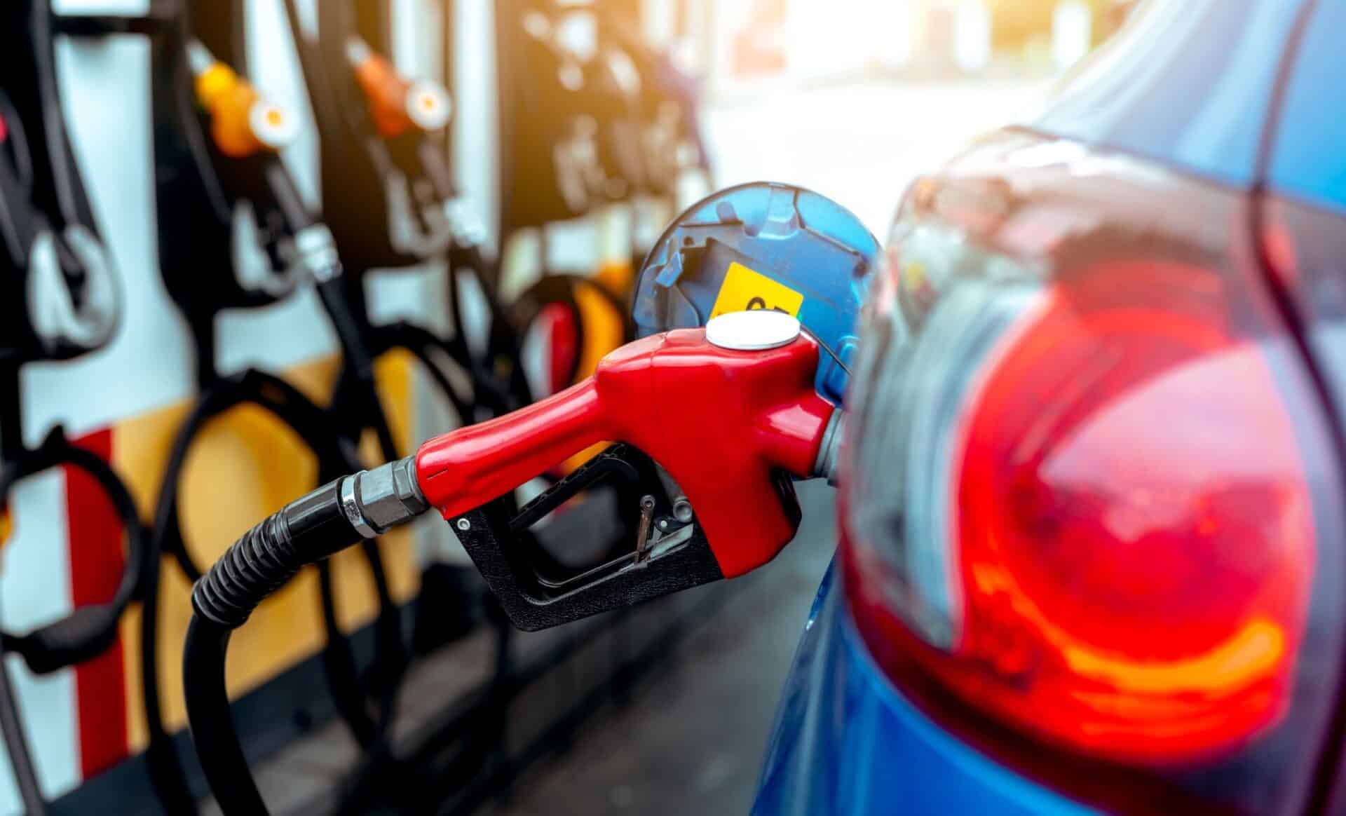 une personne qui tient un pistolet à carburants dans une station service pour illustrer le renversement du gazole et de l'essence