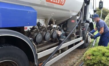 Une homme qui place un tuyeau dans un camion citerne transportant du Fioul domestique