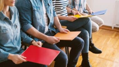 Photo de trois jeunes assis et tenant entre les mains un dossier pour évoquer le sujet des jeunes sans emploi