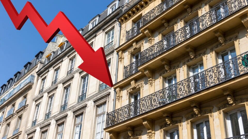 Photo d'appartements haussmanniens en arrière-plan + une flèche descendante pour illustrer la chute des ventes dans l'immobilier