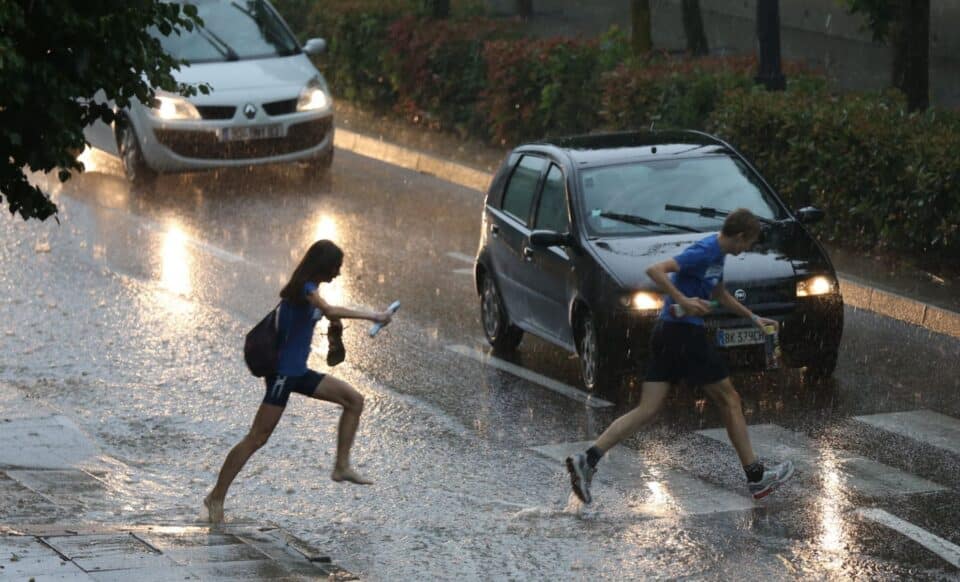 Deux piétons traversant la route sous une météo agitée