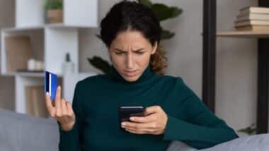 Une photo d'une femme qui tient un téléphone pour illustrer la part de responsabilité des banques lors des faux virements