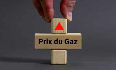 Une main plaçant un cube en bois avec une flèche rouge pointant vers le haut sur un autre cube marqué "Prix du Gaz