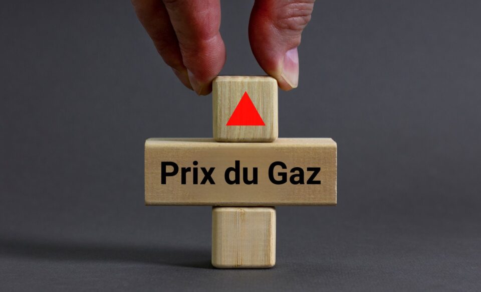 Une main plaçant un cube en bois avec une flèche rouge pointant vers le haut sur un autre cube marqué "Prix du Gaz