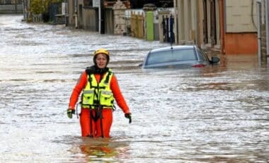 Pluie Inondation, Crues illustrée dans cette photo d'une femme qui traverse une rue inondée alors que la météo est agitée