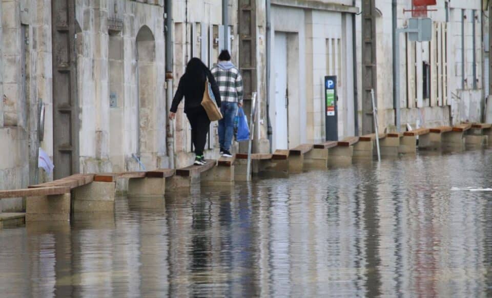 Deux personnes marchent sur une route inondée pour illustrer les alertes météo