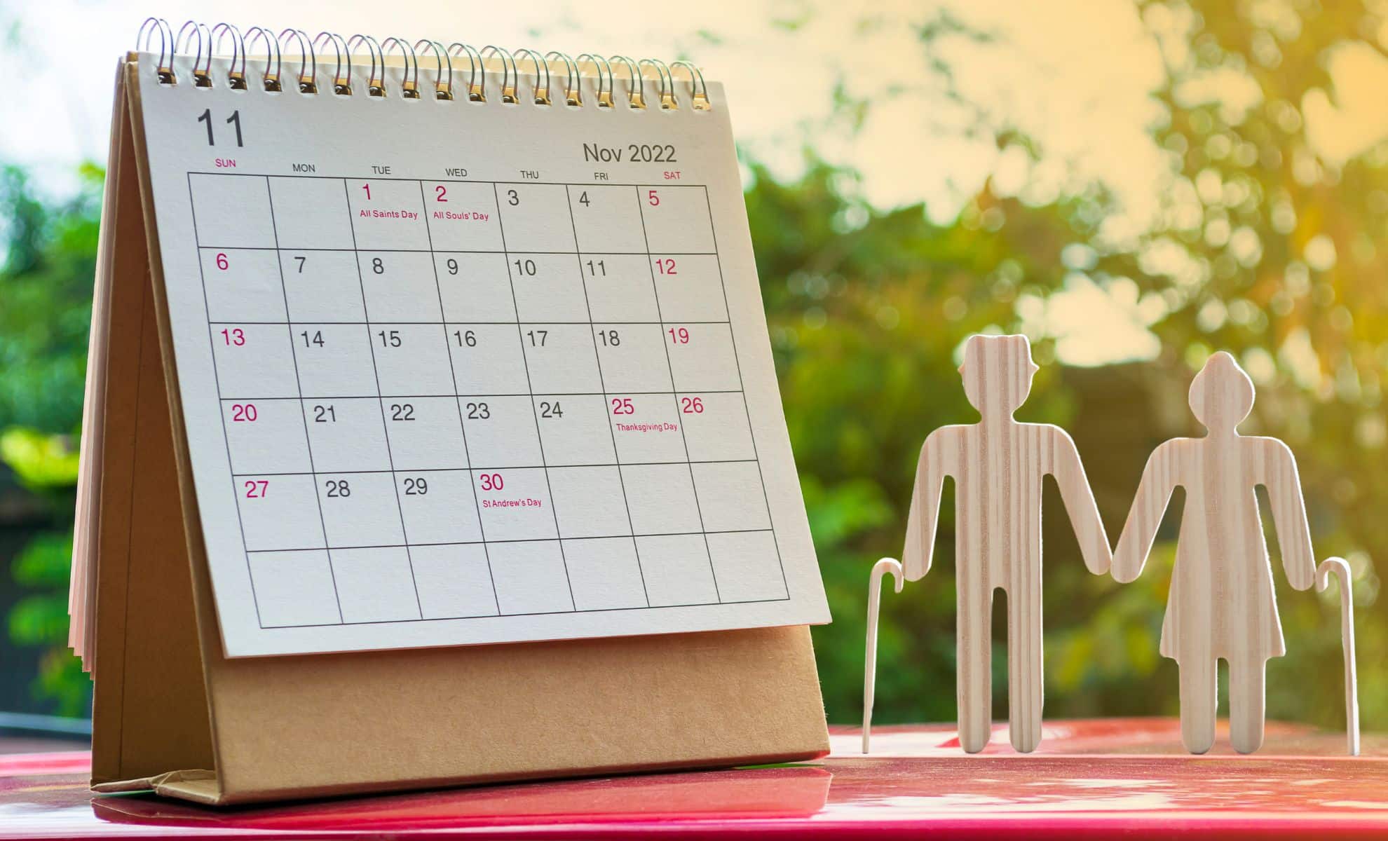 Figurines représentant des retraités à côté d'un calendrier sur un support rouge