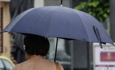 Passante s'abritant de la pluie avec un parapluie pour évoquer la météo hivernale