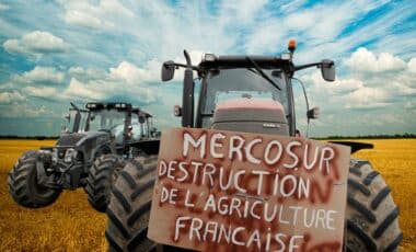 Une photo d'un tracteur avec une pancarte pour illustrer la colère des agriculteurs