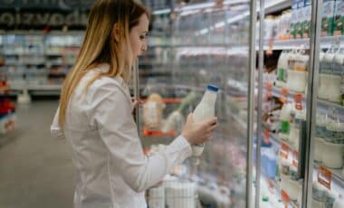 Consommatrice dans une grande surface tenant en main du lait en bouteille