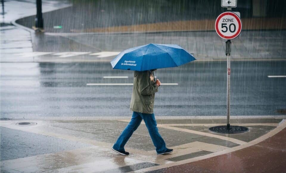 Une personne avec un parapluie marchant sous une météo fortement agitée