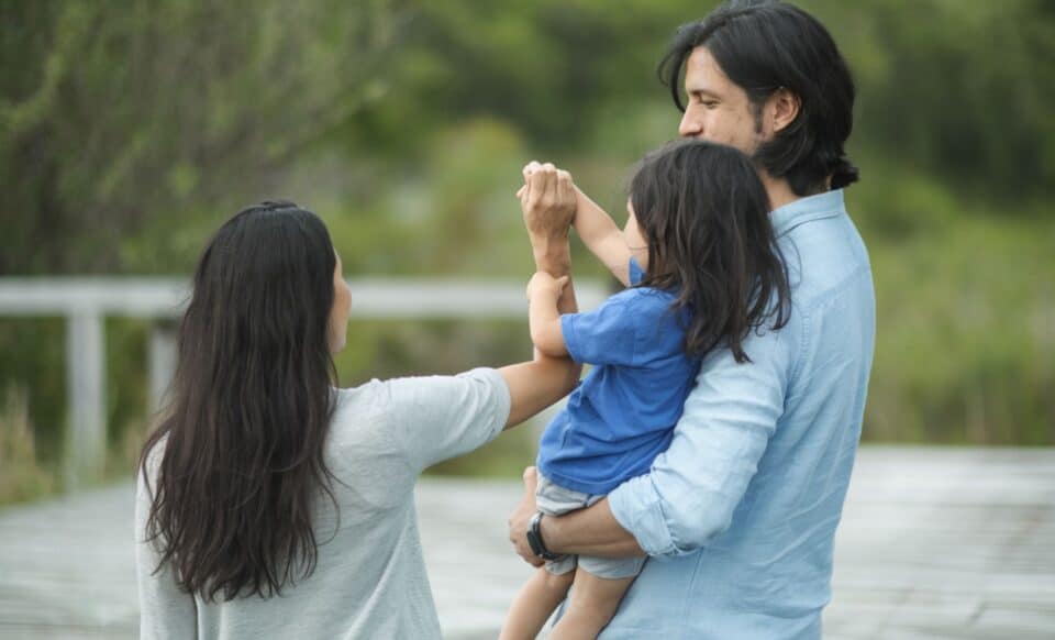 une famille de trois personnes qui se promène au parc