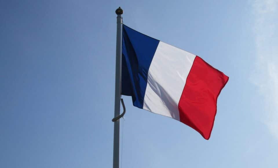 L'image montre un drapeau français flottant sur un fond de ciel bleu, symbole d'union nationale. Associé au mot-clé deuil, ce drapeau évoque une journée de recueillement ou d'hommage national, comme celle décrétée pour Mayotte après une tragédie.