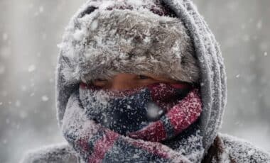 Un homme vêtu d'un bonnet et d'une écharpe sous une météo hivernale