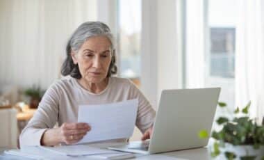 Une personne âgée devant un ordinateur et une feuille pour illustrer le sujet de la retraite et la pension de réversion