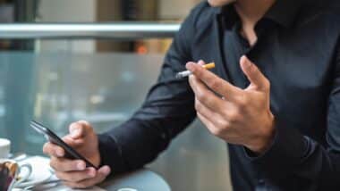 Un homme qui tient une cigarette dans sa main pour illustrer les prix du tabac