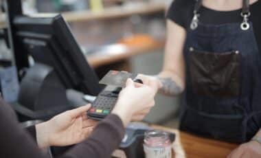 Cette image montre une scène d'achat en magasin, avec une carte bancaire ou de fidélité utilisée pour un paiement sans contact.