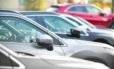 L'image montre une rangée de véhicules alignés sur un parking, illustrant un contexte lié à la mobilité des automobilistes.