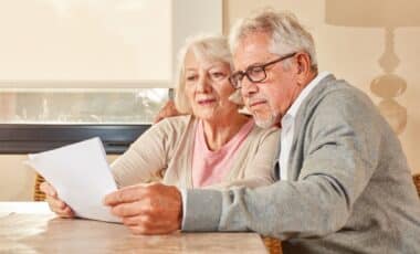 L'image montre un couple de retraités examinant attentivement un document