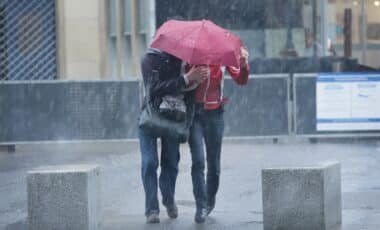 Deux personnes sous un parapluie marchant sous une météo très perturbée