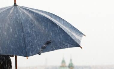 Cette image montre un parapluie sous une pluie battante, illustrant des conditions météorologiques pluvieuses. Le décor flou en arrière-plan renforce l’idée de précipitations intenses, souvent associées à une agitation météo. Le parapluie symbolise une protection face aux intempéries, en lien avec des prévisions climatiques instables.