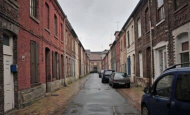 Cette image montre une rue typique de Roubaix, une ville du nord de la France. Avec ses maisons en briques rouges et son ambiance industrielle, elle reflète le passé ouvrier de la commune. Roubaix détient le triste record du taux de pauvreté le plus élevé de France, avec 46 % de sa population vivant sous le seuil de pauvreté, selon un récent rapport.