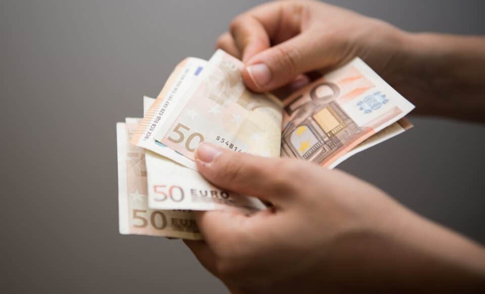 Cette image montre des mains manipulant des billets de 50 euros, pour illustrer la thématique du salaire et des aides sociales