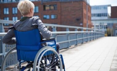 Une personne en fauteuil roulant de dos qui circule dans la rue